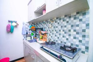 eine Küche mit Herd und gefliester Wand in der Unterkunft Harsari Syariah with Karaoke and Balcony in Batu + 12 Fotos