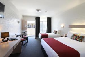 una camera d'albergo con 2 letti e una scrivania di Econo Lodge Gateway Tamworth a Tamworth