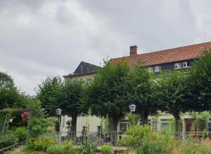une maison avec des arbres devant elle dans l'établissement Kottmarschenke - Gästezimmer und Ferienwohnung am Kottmar, à Kottmar