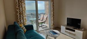 a living room with a couch and a television and a balcony at Apartment Blue Utjeha Hladna uvala in Kruče