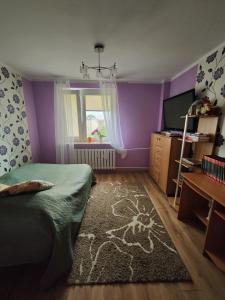 um quarto com paredes roxas, uma cama e uma janela em Słoneczny Apartament em Szczecinek