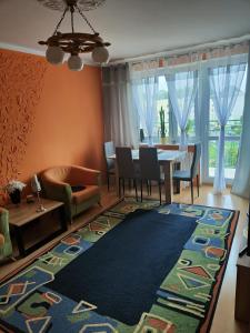 Słoneczny Apartament في شتيتشينيك: غرفة معيشة مع طاولة وكراسي وسجادة