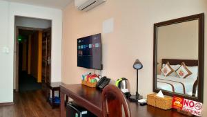een kamer met een bureau met een spiegel en een bed bij THE RICE HOTEL in Ho Chi Minh-stad