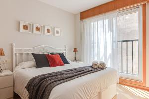 een slaapkamer met een wit bed en een groot raam bij San Amaro Beach Apartment in A Coruña