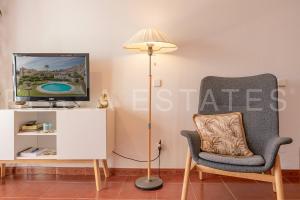 a room with a lamp and a chair and a tv at Bonito piso a 300m de la playa Nerja in Nerja