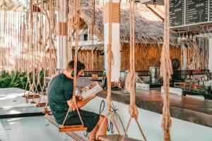 a man sitting on a swing in a restaurant at See Through Resort Haad Yao in Haad Yao