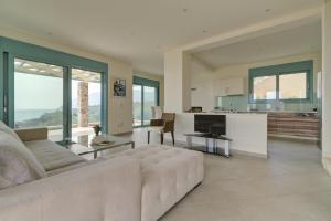 a living room with a white couch and a kitchen at Ouzo Panoramic Houses 1, with private pool in Plomarion