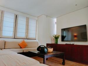 a living room with a couch and a tv at Casa Evaliza in Seminyak