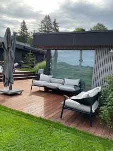 una terraza de madera con 2 sofás y una sombrilla en Le Stefanshof, en Amblève