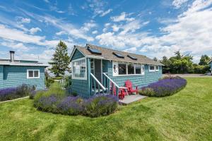 a blue tiny house in a yard with purple flowers at Juan de Fuca Cottages in Sequim