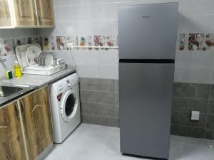 a kitchen with a refrigerator and a washing machine at Al Rawda Apartments -Ajman in Ajman 