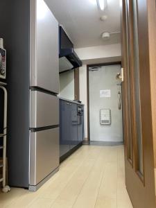 a kitchen with a refrigerator and a door to a hallway at First Hiroshima in Hiroshima