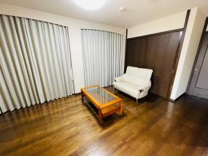 een woonkamer met een witte stoel en een salontafel bij Prime 糸島 in Itoshima