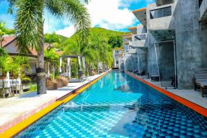 una piscina en un complejo con palmeras en See Through Resort Haad Yao, en Haad Yao