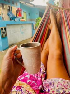 a person laying on a hammock holding a cup of coffee at NEW CORALs in Gili Trawangan