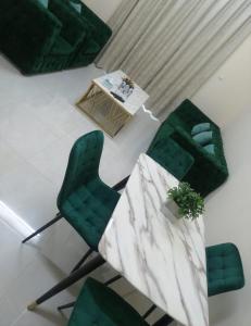 a living room with green chairs and a table at Al Rawda Apartments -Ajman in Ajman 