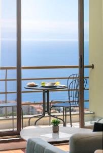 a table and chair on a balcony with a view of the ocean at Caniço VII - Desertas View in Santa Cruz