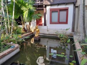 a house with a koi pond in a garden at Ayutthaya Garden River Home in Ban Bang Krasan