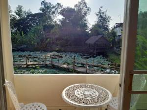 einen Blick auf einen Teich aus einem Fenster mit einem Tisch und Stühlen in der Unterkunft Ayutthaya Garden River Home in Ban Bang Krasan