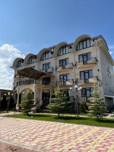 un grande edificio con alberi di fronte di Гостевой дом RAZAM a Bosteri
