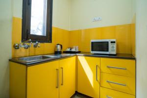 Żółta kuchnia ze zlewem i kuchenką mikrofalową w obiekcie Enkay Residency V Block-Cyber City w mieście Gurgaon