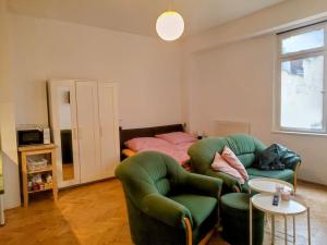 a living room with a green chair and a bed at Cosy warm apartment in the heart of Prague. in Prague