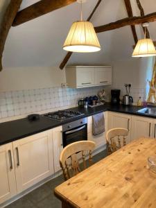 a kitchen with white cabinets and a wooden table at Stable Cottage - near Lulworth Cove in Dorchester