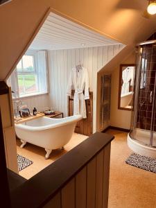uma grande casa de banho com banheira e um roupão pendurado na parede em The Foulsyke Licensed Bed and Breakfast Scalby Scarborough em Scarborough