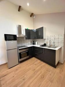 a kitchen with black and white appliances and wooden floors at Dépendance corps de ferme in Naucelles +1 photo