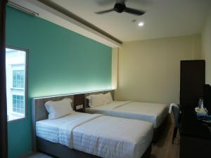 Pantai Regal City Hotel في كُوانتان: سريرين في غرفة الفندق مع مروحة سقف