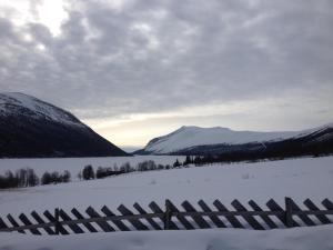 una cerca en un campo nevado con montañas en el fondo en Mountain cabin Skoldungbu, en Vang I Valdres
