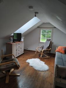 ein Wohnzimmer mit 2 Stühlen, einem TV und einem weißen Teppich in der Unterkunft Villa Koskikorento in Kannus