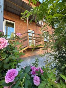 a brick building with a balcony and pink roses at Міні-готель "Садиба" in Sumy