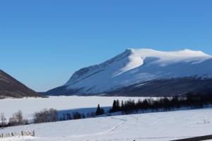 una montaña cubierta de nieve frente a un cuerpo de agua en Mountain cabin Skoldungbu, en Vang I Valdres