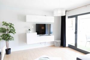 ein weißes Wohnzimmer mit einem TV an der Wand in der Unterkunft Modern apartment, Pool & Air con, San Juan Playa in Alicante