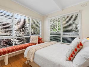 a bedroom with a bed and a bench and windows at Bella Rye by Ready Set Stay - BYO LINEN & TOWELS in Rye +13 photos