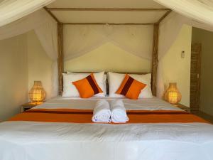 Schlafzimmer mit einem Bett mit orangefarbenen und weißen Kissen in der Unterkunft Comeon Amed in Amed