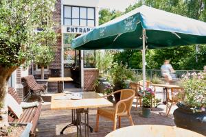 a patio with tables and chairs and an umbrella at Hotel Station Amstelveen in Amstelveen