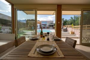 a dining table with plates and wine glasses on a patio at Modular Bungalows With Heated Pool Artemis Greece in Artemida