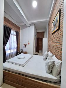 a bedroom with a large bed with a brick wall at MIN Guest House Watukarung in Pacitan