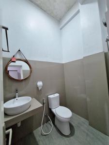 a bathroom with a toilet and a sink and a mirror at MIN Guest House Watukarung in Pacitan