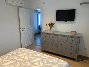 um quarto com uma cómoda e uma televisão na parede em Villa Delfin em Vis