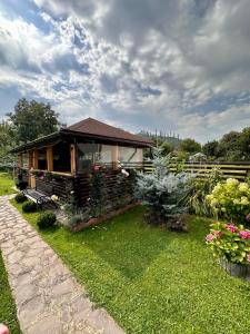 mały domek na podwórku z kwiatami i roślinami w obiekcie Pensiunea Stoian w mieście Cristian
