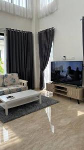 a living room with a couch and a tv at 4BR Private Villa with Pool in the Heart of city in Batu Ampar