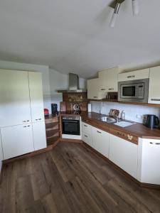 cocina con armarios blancos y suelo de madera en Schroider en Kössen