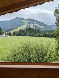 una ventana con vistas a un campo y a las montañas en Schroider en Kössen