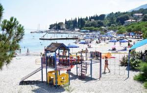 a playground on a beach with people in the water at Palmgarden Apartments Opatija-Ičići in Opatija