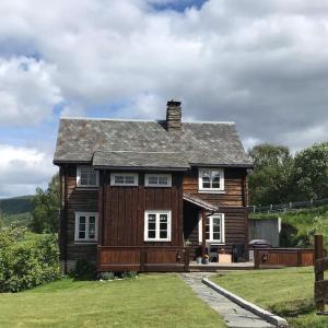 una piccola casa in legno su un prato di The Olav-house from 1840, at farm Ellingbø a Vang I Valdres