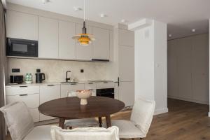 uma cozinha com armários brancos e uma mesa e cadeiras de madeira em Metro Kabaty Elegant Apartment em Varsóvia