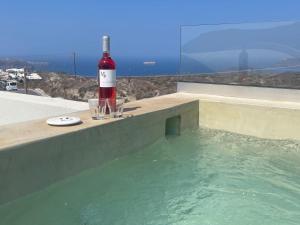 een fles wijn en glazen op een richel bij Lejardin suites santorini in Pirgos